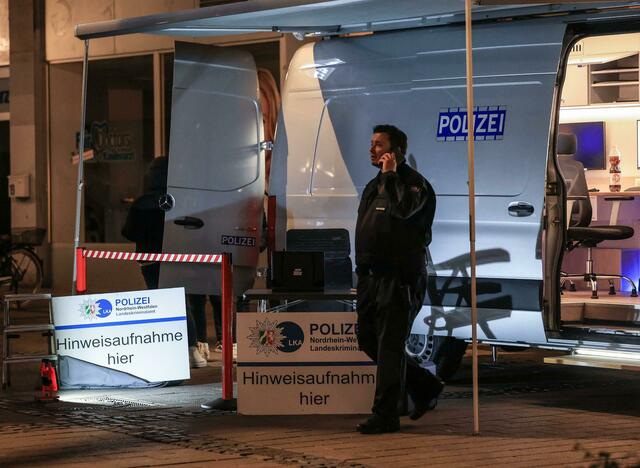 Ein Polizist steht in der Nähe des Tatortes vor einem Einsatzfahrzeug.  | Foto: Oliver Berg/dpa