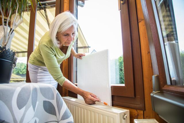 Die Wand hinter einem Heizkörper lässt sich mit Dämmstoffplatten isolieren - und so geht weniger Heizwärme verloren.  | Foto: Christin Klose/dpa-mag