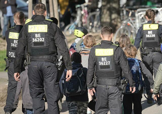 Polizisten geleiten Kinder weg vom Tatort an der Schule in Berlin-Neukölln.  | Foto: Michael Kappeler/dpa