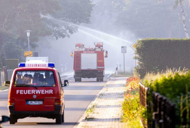 Feuerwehrfahrzeuge in der evakuierten Ortschaft Volzrade, durch die Rauch vom Waldbrand auf dem ehemaligen Truppenübungsplatz zieht.  | Foto: Jens Büttner/dpa