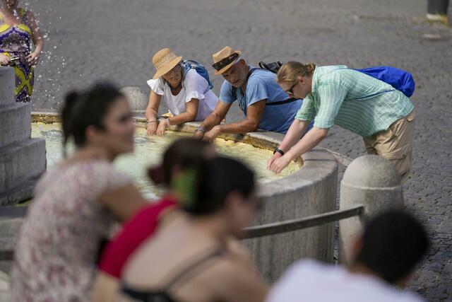 Touristen erfrischen sich bei ihrem Besuch in Rom an einem Brunnen. | Foto: Andrew Medichini/AP