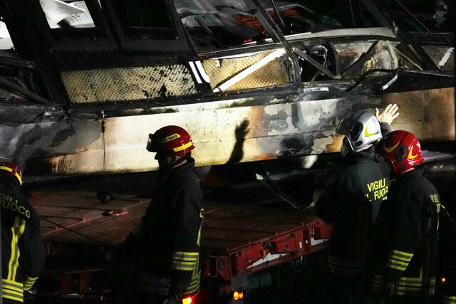 Feuerwehrleute arbeiten nach dem Busunglück an der Unfallstelle.  | Foto:  Antonio Calanni/AP