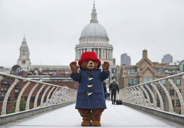 Ein Darsteller im Kostüm des Paddington-Bär auf der Millenium-Brücke vor der Kuppel der St.-Pauls-Kathedrale in London. | Foto: Frank Augstein/AP/dpa