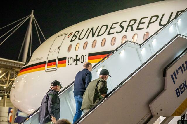 Bodyguards bringen Bundeskanzler Olaf Scholz nach dem Luftalarm in den Regierungs-Airbus.  | Foto: Michael Kappeler/dpa Pool/dpa