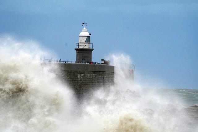 Wellen schlagen vor dem Leuchtturm an die Hafenmauer in Folkstone.  | Foto: Gareth Fuller/PA Wire/dpa