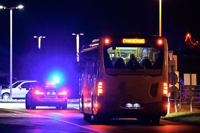 Ein Polizeiauto eskortiert einen Bus mit Menschen vom Flughafen Hamburg.  | Foto: Jonas Walzberg/dpa