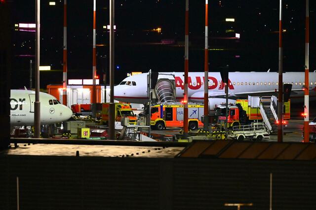 Fahrzeuge der Feuerwehr und ein Krankenwagen stehen am Flughafen vor einem Flugzeug.  | Foto: Jonas Walzberg/dpa