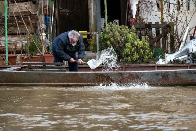 Ein Anwohner an der Fischerei in Bamberg schöpft Wasser aus einem Boot.  | Foto: Pia Bayer/dpa