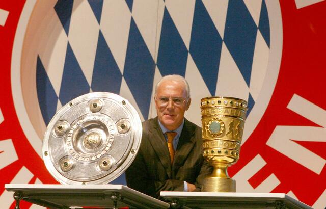 Der damalige FCB-Präsident, Franz Beckenbauer, steht zwischen Meisterschale und DFB-Pokal.  | Foto: Frank Mächler/dpa/Archivbild