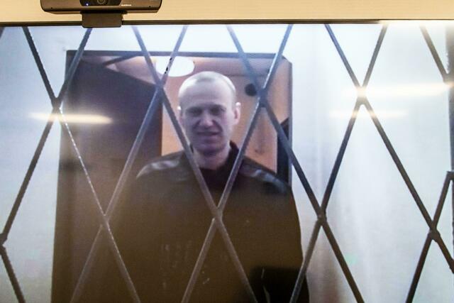 Alexej Nawalny ist auf einem Fernsehbildschirm zu sehen, als er per Video aus einem Gerichtssaal erscheint. | Foto: Antonina Favorskaya/AP/dp