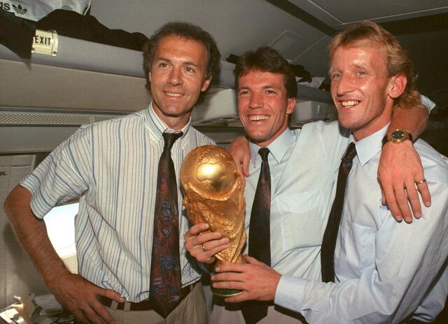 Im Flugzeug präsentieren der damalige DFB-Teamchef Franz Beckenbauer (l), Lothar Matthäus (M) und Andreas Brehme den WM-Pokal.  | Foto: Wolfgang Eilmes/dpa