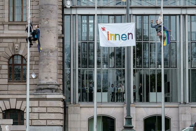 Zwei Schülerinnen haben einen Fahnenmast außen vor der Bayerischen Staatskanzlei in München erklommen.  | Foto: Thomas Vonier/SZ/dpa