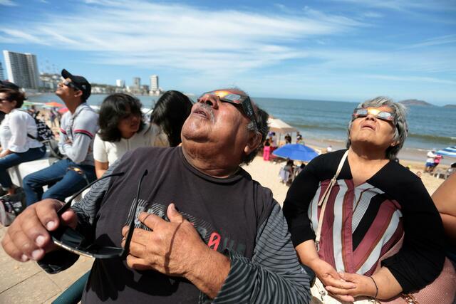 Menschen haben sich im Hafen von Mazatlán in Mexiko versammelt, um die totale Sonnenfinsternis beobachten.  | Foto: Eduardo Resendiz/dpa