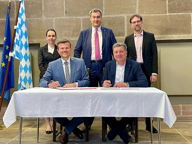 Oberbürgermeister Marcus König und der bayerische Verkehrsminister Christian Bernreiter (vorne, v.l.) unterzeichnen im Beisein von Bayerns Ministerpräsidenten Dr. Markus Söder (Mitte) sowie Wirtschaftsreferentin Dr. Andrea Heilmaier und Baureferent Daniel F. Ulrich den Letter of Intent für eine Machbarkeitsstudie für eine Magnetschwebebahn in Nürnberg. | Foto: Andreas Franke / Stadt Nürnberg