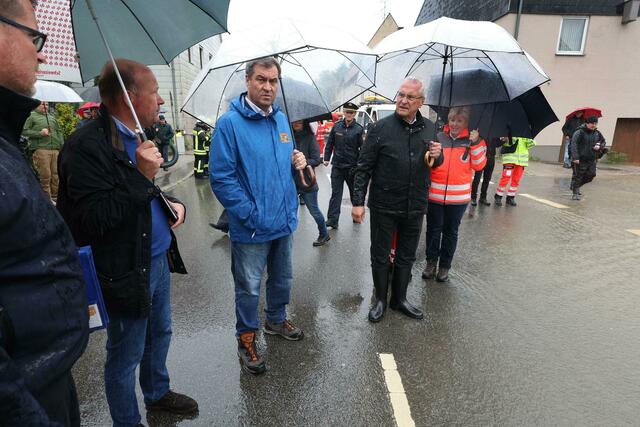 Markus Söder (CSU, l), bayerischer Ministerpräsident und Joachim Herrmann, bayerischer Innenminister (CSU, M), stehen am Rande einer überfluteten Straße. Söder dankte bei seinem Besuch in Diedorf (Landkreis Augsburg) insbesondere den Hilfskräften und den Behörden. Bayern sei krisenerprobt.  | Foto:  Karl-Josef Hildenbrand/dpa