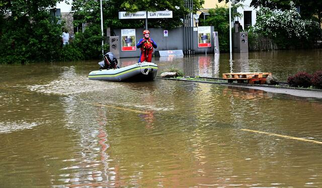 Ein Helfer kommt mit dem Schlauchboot zu einer überschwemmten Tankstelle in Allershausen.  | Foto:  Felix Hörhager//dpa