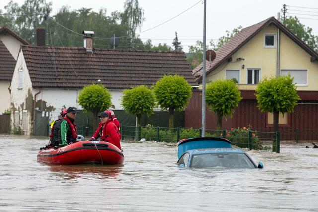 Die Wasserwacht fährt mit einem Schlauchboot durch eine überflutete Straße. Bayerns Ministerpräsident Markus Söder und Landesinnenminister Joachim Herrmann reistem am Samstag in das Hochwassergebiet im schwäbischen Landkreis Augsburg. In Diedorf wollten sich die beiden CSU-Politiker selbst ein Bild von der Hochwasserentwicklung machen, wie das Innenministerium mitteilte. An dem Termin nahm auch Landrat Martin Sailer teil. | Foto: Stefan Puchner/dpa