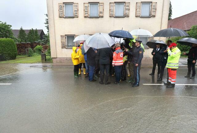 Markus Söder (verdeckt) steht, umringt von Journalisten, am Rande einer überfluteten Straße. In mehreren Kommunen des Landkreises Augsburg sind weitere Menschen wegen des akuten Hochwassers angehalten, ihre Wohnungen und Häuser zu verlassen. Die Lage werde sich am Abend im nördlichen Teil des Landkreises noch verschärfen, sagte eine Sprecherin des Landratsamtes Augsburg. Teile von Batzenhofen, Gablingen, Langweid, Eisenbrechtshofen, Biberbach, Allmannshofen und die gesamte Gemeinde Nordendorf seien betroffen.  | Foto: Karl-Josef Hildenbrand/dpa