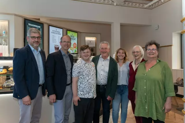 Gemeinsam auf dem Weg. Mit der Unterzeichnung des Pachtvertrags ist das Ludwigscafé einen großen Schritt näher gerückt.
(v.l.n.r.) Rolf Bidner (Geschäftsführer Lebenshilfe Fürth), Marcus Steurer (Geschäftsführer infra), Merlin Mücke (Servicekraft), Oberbürgermeister Dr. Thomas Jung (Aufsichtsratsvorsitzende Lebenshilfe Fürth), Kerstin Ritschke (Werkstattleiterin Dambacher Werkstätten) sowie Andrea Zieger (stv. Aufsichtsratsvorsitzende) und Mic A. Clar (Caféleitung) freuen sich auf die zukünftige Zusammenarbeit im Herzen der Stadt. | Foto: infra Fürth