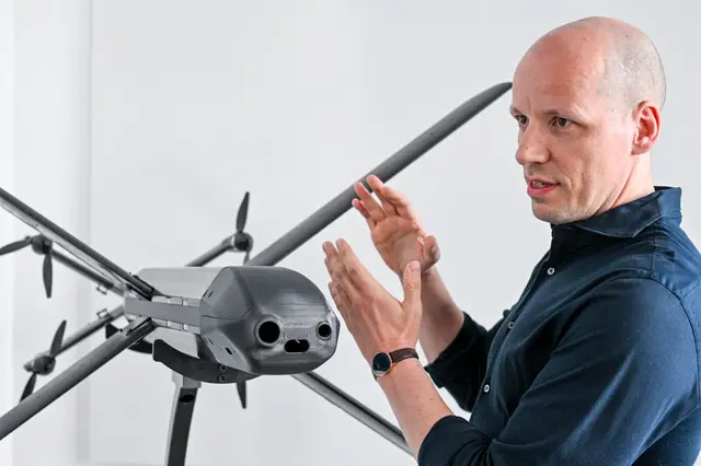 Ein Modell der HX-2-Drohne von Helsing, daneben der Mitgründer und Co-Firmenchef Gundbert Scherf. | Foto: Jens Kalaene/dpa