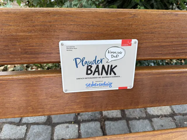 Die erste Plauderbank steht in Nürnberg auf dem Sebalder Platz. Sie wurde am Donnerstag, 17. Juli 2025, der Öffentlichkeit übergeben. Ein Schild weist auf den Zweck hin. | Foto: Tim Koß / Stadt Nürnberg