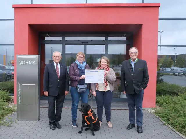 Mirjam Schuh (2. v. r.), Schulleitung, Astrid Bartholomeyczik (2. v. l.), Schulsozialpädagogin, und Labrador-Hündin Akemi nahmen die Spende im Namen der Grundschule Maistraße entgegen. Stiftungsvorstand Dr. Wilhelm Polster (l.) und Stiftungsrat Klaus Teichmann (r.) überreichten den Spendenscheck persönlich.
 | Foto: © NORMA