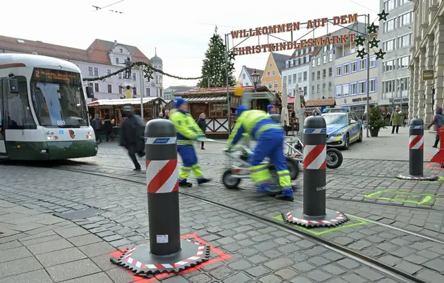 Zu den Hauptverkehrszeiten müssen Sicherheitsmitarbeiter neben dem Augsburger Christkindlesmarkt jede Stunde dutzendfach schwere Poller bewegen, damit die Straßenbahnen durchfahren können. | Foto: Malin Wunderlich/dpa