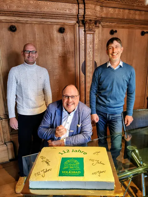 Bürgermeister und Erster Werkleiter von NürnbergBad, Christian Vogel (Mitte), probiert die Geburtstagstorte zum 112. Geburtstag des Volksbads. Beim Anschneiden der Torte helfen der Technische Werkleiter Helmut Blaß (l.) und der Kaufmännische Werkleiter Matthias Bach (r.). | Foto: Christian Pröbiuß / Stadt Nürnberg / NüBad