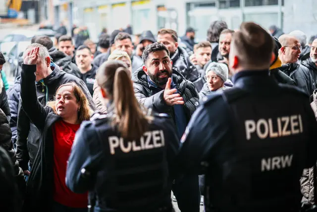 Aufgebrachte Kunden diskutieren vor der Sparkassenfiliale in Buer mit Polizeibeamten nach der Räumung des Vorraums der Filiale. | Foto: Christoph Reichwein/dpa