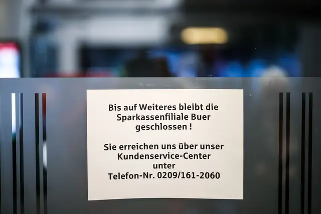 Aufgebrachte Kunden diskutieren vor der Sparkassenfiliale in Buer mit Polizeibeamten nach der Räumung des Vorraums der Filiale. | Foto: Christoph Reichwein/dpa