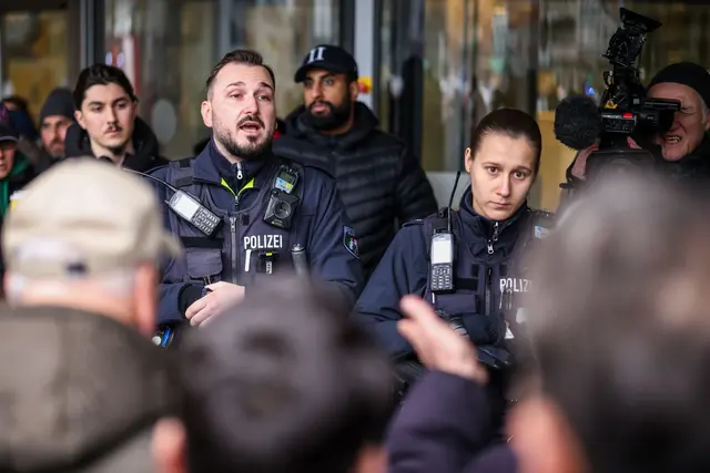 Aufgebrachte Kunden diskutieren vor der Sparkassenfiliale in Buer mit Polizeibeamten nach der Räumung des Vorraums der Filiale. | Foto: Christoph Reichwein/dpa