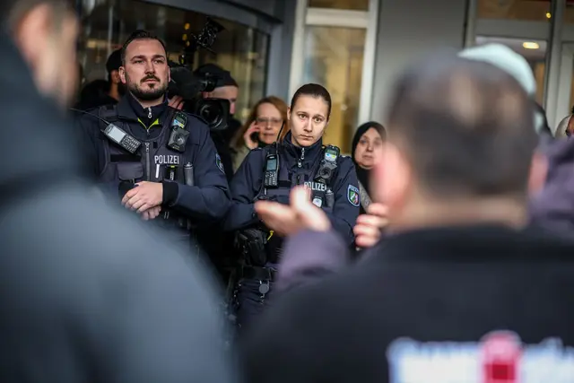 Aufgebrachte Kunden diskutieren vor der Sparkassenfiliale in Buer mit Polizeibeamten nach der Räumung des Vorraums der Filiale. | Foto: Christoph Reichwein/dpa