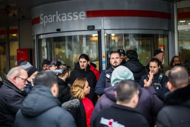 Aufgebrachte Kunden diskutieren vor der Sparkassenfiliale in Buer mit Polizeibeamten nach der Räumung des Vorraums der Filiale. | Foto: Christoph Reichwein/dpa