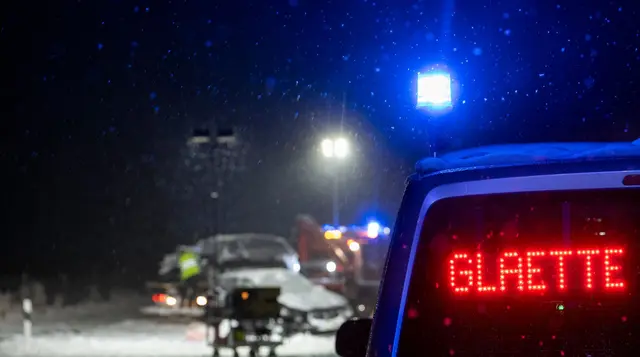 Auf der verschneiten Bundesstraße 12 warnt an einer Unfallstelle ein Polizeifahrzeug vor Glätte. | Foto: Stefan Puchner/dpa
