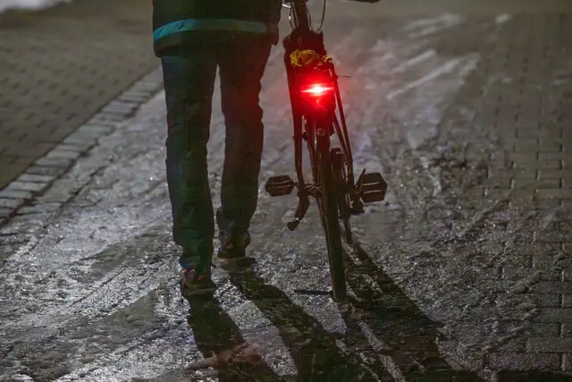 Ein Mann schiebt sein Fahrrad auf einer vereisten Straße. | Foto: Armin Weigel/dpa