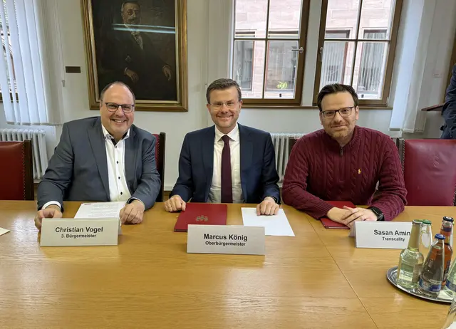 Oberbürgermeister Marcus König (Mitte), Bürgermeister und Erster Sör-Werkleiter Christian Vogel (links) und Sasan Amini, Co-Founder des Softwareherstellers Transcility (rechts) haben am Donnerstag, 26. Februar 2026, den Vertrag zum Pilotprojekt unterzeichnet. | Foto: Tim Koß / Stadt Nürnberg