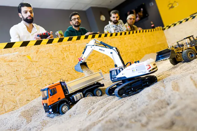 Gründer Siymo Othman (links) steuert mit Freunden kleine Bagger, Radlader und Lastwagen in seinem neu eröffneten Bagger-Café. Es soll das erste dieser Art in Deutschland sein. | Foto: Moritz Frankenberg/dpa