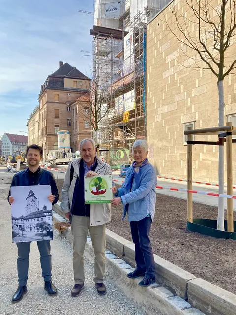 Baummanager vom Servicebetrieb Öffentlicher Raum Nürnberg, Florian Demling, sowie die Vertreter der Bäume für Nürnberg Stiftung, Vorstandsvorsitzender Mathias Schmidt und Stiftungsgründerin Margit Grüll (v.l.), vor dem Volksbad Nürnberg mit den beiden von der Stiftung gespendete Bäumen im Hintergrund. | Foto: Dr. Christian Pröbiuß / Stadt Nürnbe