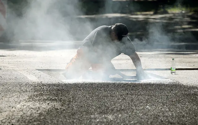 Ein Bauarbeiter repariert eine Straße in Berlin mit Bitumen, einem Bindemittel für Asphalt. (Symbolbild) | Foto: Wolfgang Kumm/dpa