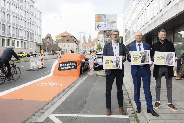 Ein roter Fahrradweg-Teppich verläuft über ein falsch geparktes Auto auf einem Radweg an der Marienstraße. Die Kampagne "Verstell dich nicht – Respekt hat Effekt" haben der Leiter des Verkehrsplanungsamts, Frank Jülich, Bürgermeister Andreas Krieglstein und der Fraktionsvorsitzende der Grünen im Stadtrat, Alexander Kahl (v.l.) vorgestellt.
 | Foto: Giulia Iannicelli / Stadt Nürnberg