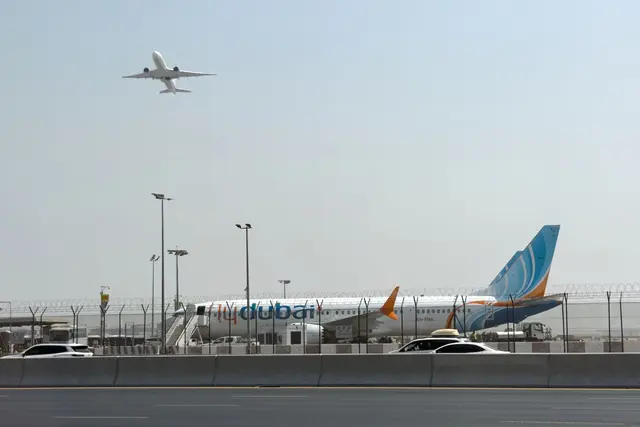 Ein Flugzeug hebt ab, während ein Flydubai-Flieger in Dubai auf dem Flughafen steht. | Foto:  Uncredited/AP/dpa